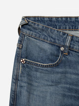 Close-up of the BGrepi Presley Jeans - Denim Blue by Blue de Gênes, showcasing a small front pocket with a stitched patch featuring a white X on a red and brown background. These durable slim-fit jeans are made from comfort stretch denim and include visible seams and a belt loop.