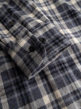 A close-up of the BGenrico Hang Shirt - Navy Check by Blue de Gênes showcases a blue, gray, and white check cuff with two black buttons. The 100% cotton fabric looks soft and slightly textured, highlighting the shirt’s comfort.