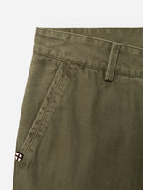 Close-up of the BGmenzo Rory Chino - Army by Blue de Gênes, highlighting the olive green washed herringbone fabric, front pocket, belt loop, and a distinctive small patch with a red cross on a white background stitched near the pocket. Designed in a classic chino fit for versatile styling with your matching blazer.
