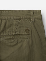 Close-up of the back pocket and waistband of the Blue de Gênes BGmenzo Rory Chino - Army, showcasing olive green washed herringbone fabric in a classic chino fit with belt loops and a small embroidered shield emblem above the pocket.