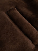 Close-up of the dark brown suede fabric on the BGseras Shearling Coat by Blue de Gênes, featuring a rectangular slit that may be a pocket or seam detail. The soft, slightly fuzzy texture is characteristic of high-quality shearling designed for cold-weather wear.