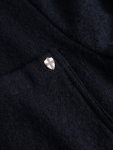 Close-up of the BGlewis Wool Blazer in Dark Navy by Blue de Gênes, showcasing its relaxed double-breasted tailoring and a small metallic shield pin with a cross attached near the seam or pocket.