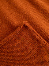 Close-up of the BGgordon Knit in Ginger Bread Orange by Blue de Gênes, highlighting its textured wool fabric, visible seam, and folded edge that showcases the distinctive weave. The crew neck design enhances the classic appeal of this embroidered sweater.