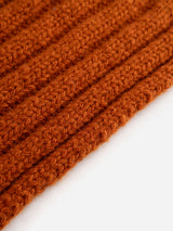 Close-up of the textured, ribbed fabric of the BGcomforto Knit Scarf in Ginger Bread Orange by Blue de Gênes, set against a plain white background.