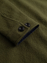 Close-up of the BGhew Wool Overshirt - Winter Moss by Blue de Gênes, highlighting the green boiled wool sleeve with two black buttons, visible buttonholes, fine fabric texture, and dark lining inside the cuff.