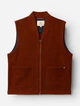 The BGmudock Wool Waistcoat in Ginger Bread Orange by Blue de Gênes is a rust-colored, workwear-inspired vest with a zip-up front, two pockets (one adorned with a small metal pin), and dark fabric lining. It is laid flat on a plain white background.