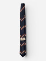 Introducing the BGcarl Tie - Dark Navy by Blue de Gênes, a luxurious silk tie in deep navy adorned with elegant diagonal stripes in red, white, and light blue. Neatly folded and secured with a beige label featuring a subtle logo and text, this striking diagonal stripe tie stands out beautifully against the plain white background.
