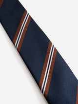 The BGcarl Tie - Dark Navy by Blue de Gênes features diagonal brown and white stripes against a navy blue silk background, displayed on a plain white backdrop.