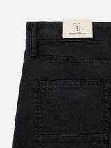 Close-up of the back pocket and waistband of navy BGvinci Iro Pant by Blue de Gênes, showcasing a beige label with a small crest logo above the brand name attached to the waistband. Crafted from comfort stretch twill, these regular fit pants combine style with ease of movement.