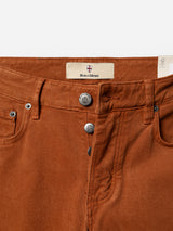 Close-up of the BGvinci Iro Pant in Ginger Bread Orange by Blue de Gênes, crafted from comfort stretch twill and designed with silver buttons, a signature Blue de Gênes label, front pockets, and belt loops, displayed against a white background.