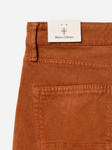 Close-up of the BGvinci Iro Pant in Ginger Bread Orange, crafted from comfort stretch twill denim with a regular fit. These jeans by Blue de Gênes showcase a visible back pocket, belt loop, and a signature brand tag featuring a small crest tucked beneath the waistband.