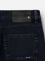 The BGvinci Black OD Jeans by Blue de Gênes feature blue-black stretch denim, a back pocket, and a black leather waistband patch with the Blue de Gênes logo and red and white shield emblem.