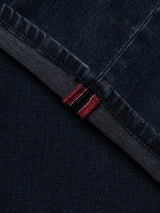 Close-up of the BGgiacomo BB Jeans - Blue Black Denim by Blue de Gênes, crafted from rigid denim with a relaxed loose fit. The image showcases the folded cuff, highlighting the exposed red and white selvedge edge stitching against a dark background.