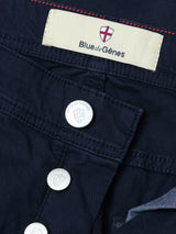 Close-up of the BGpaulo Teo Pant in Dark Navy by Blue de Gênes, showing the vintage military-inspired cotton chino fabric, detailed stitching, metal buttons, and a label featuring the Blue de Gênes name alongside a red and white shield logo.