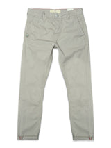 The Blue de Gênes BGpaulo Teo Pant in Shadow Green is laid flat, showcasing a slim-fit silhouette with a front button closure, belt loops, pockets, and subtle red accents near the ankle hems—crafted as durable chinos inspired by vintage military pants.
