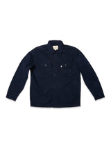 The BGpontus Teo Overshirt by Blue de Gênes is a dark navy button-up style featuring long sleeves, a collar, and two front chest pockets with flaps and buttons. Crafted from honeycomb cotton for added texture and comfort, its relaxed fit makes it an effortless layering piece. Photographed laid flat on a white background.