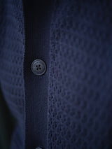 Close-up of the BGbilly S/S Cardigan in Dark Navy by Blue de Gênes, highlighting the textured knit fabric and a single round button fastened at the center, with a focus on the fine details of both the material and button stitching.