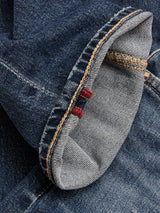 Close-up of BGvinci Striker Jeans - Dark Distress by Blue de Gênes, featuring blue comfort stretch denim with a folded cuff, yellow stitching, and two small red threads on the seam. The fabric texture and weave are clearly visible, highlighting the regular fit jeans design.