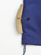 A close-up of the BGcanopy Jacket - Navy Peony by Blue de Gênes showcases a pocket with a beige interior lining, detailed with a buttonhole, a black button, and a blue and white braided drawstring visible at the bottom.