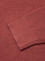 Close-up of the Blue de Gênes Porto Polo Knit in Henna, showcasing the sleeve cuff and intricate pattern of this luxury sweater as it lays flat on matching fabric.