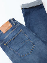 A pair of Recco Blue Vintage Jeans in vintage wash by Blue de Gênes is laid flat with one leg cuffed, showing the back pocket and a tan leather patch on the waistband—crafted from comfort denim for easy wear.