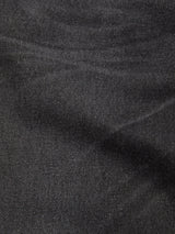 Close-up of grey denim fabric from the Giacomo BLK Used Jeans by Blue de Gênes, highlighting its textured weave and subtle diagonal lines, with soft folds and gentle shading across the surface.