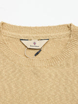 Close-up of the BGyale Slubby Crewneck Knit in Pale Khaki by Blue de Gênes, featuring a ribbed neckline, inner label with shield emblem, and a black and white string loop.