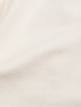 Close-up of the BGbaio Twill Blazer - Chalk by Blue de Gênes, crafted from cream-colored cotton twill with fine diagonal ribbing and gentle folds, revealing its subtle texture under soft lighting.