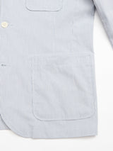 Close-up of the Blue de Gênes Gabbiano Riga Blazer - Blue Stripe, featuring light blue and white cotton yarn-dyed stripes, a large front pocket, button, and sleeve detail against a white background.
