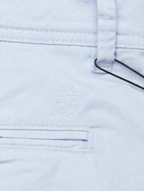 Close-up of Blue de Gênes Menzino Shorts - Blue Water: light blue herringbone fabric, stitched shield emblem with cross, belt loop, and part of welt pocket with visible black string.