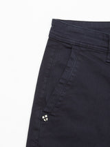 Close-up of the Blue de Gênes Menzo Dobby Chino in dark navy, highlighting the waistband, belt loop, and side pocket with a small decorative metal emblem near the seam against a white background.