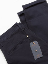 The Blue de Gênes Menzo Dobby Chino in dark navy features a back pocket, belt loop, and designer tag—style and comfort stretch chinos displayed neatly on a white surface.