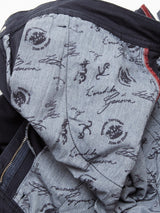 Close-up of a jacket’s inner lining in grey with black sketches—anchors, stamps, and cursive text—echoing the thoughtful detailing found in the Blue de Gênes Menzo Dobby Chino - Dark Navy. Visible zipper and red seam add contrast.