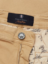 Close-up of Menzo Dobby Chino - Khaki by Blue de Gênes, featuring comfort stretch fabric, metal button, zipper, and branded navy label. The inner lining showcases cursive script and map-inspired illustrations for vintage appeal.