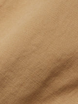 Close-up of khaki fabric with a textured weave and gentle folds, showcasing the vintage style of the Blue de Gênes Menzo Dobby Chino - Khaki, enhanced by subtle shadows and highlights.