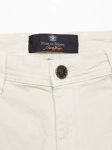 Close-up of the waistband of the Menzo Dobby Chino - Stone by Blue de Gênes, showing a dark brand label, engraved metal button, belt loops, and vintage-style stitching for added detail.