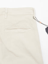 Close-up of the back pocket area of the Blue de Gênes Menzo Dobby Chino - Stone, featuring beige stretch cotton, a single welt pocket, belt loops, and a black tag attached with a string and bead.