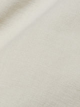 Close-up of the Menzo Dobby Chino - Stone by Blue de Gênes, showing its light beige textured fabric with a subtle diagonal fold—ideal for timeless, comfortable stretch chinos.