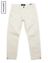 The Blue de Gênes Menzo Dobby Chino in Stone features a straight-leg cotton-stretch fit, side pockets, button closure, and rolled-up cuffs. Laid flat on white with a THE CLASSICS label for a timeless vintage touch.