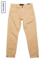 A pair of khaki Menzo Dobby Chino pants by Blue de Gênes, made from comfort stretch cotton with a vintage look, side pockets, button and zip closure, and THE CLASSICS label on the left, laid flat on a white background.
