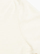 Close-up of Monte Knit - Whitecap by Blue de Gênes: light cream fabric with a visible seam, subtle texture, and fine stitching along the curved edge. The material appears soft and slightly sheer.