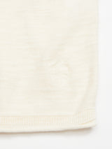 Close-up of the Monte Knit - Whitecap by Blue de Gênes, showing the cream-colored knit fabric’s edge with a subtle shield-like stitched emblem near the hem.
