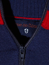 Close-up of the Tributo Cycling Jersey - Navy by Blue de Gênes, featuring navy blue knit fabric, a partially unzipped zipper, a black label reading Rue de Genève with a white shield emblem, and red accents near the collar.