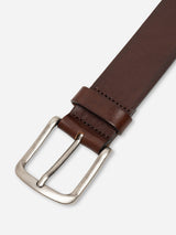 A close-up of the BGathol Belt - Dark Brown by Blue de Gênes, crafted in Italy from full-grain leather and featuring a classic metal buckle, displayed diagonally on a white background.