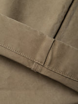 Close-up of the beige fabric from the BGliam Nebraska Chino - Brown by Blue de Gênes, showing visible stitching and a folded hem. Made from high-quality cotton or a cotton blend, the garment features subtle details such as an adjustable buckle strap for a tailored fit.