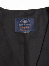 Close-up of a Black Canna Carbonio Gillet by Blue de Gênes, featuring a navy label with the brand name, "Progetto Heritage," size 50, and additional text stitched inside the collar.
