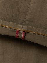 Olive green enzyme-washed BGpaulo Pavia V3 Chino - Beech Green pants cuff with a yellow stitched seam and a small red fabric tab.