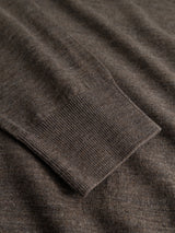A close-up of the BGigor Polo Knit - Sepia Tint Brown by Blue de Gênes, showing its fine-gauge brown knit sleeve with a ribbed cuff, laid flat against a matching fabric background.