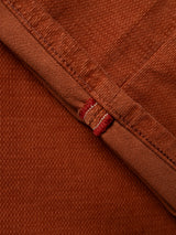 Close-up of folded Ginger Bread Orange denim fabric from the BGpaulo Ottawa V3 Trousers by Blue de Gênes, featuring visible stitching and a hint of red and white selvedge edge—evoking the refined texture characteristic of slim fit chino or dobby corduroy pants.