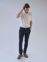 Man wearing a white t-shirt, midnight blue BGpaulo Pavia V3 Chino - Midnight Blue enzyme washed vintage military chinos, and brown tasseled loafers.